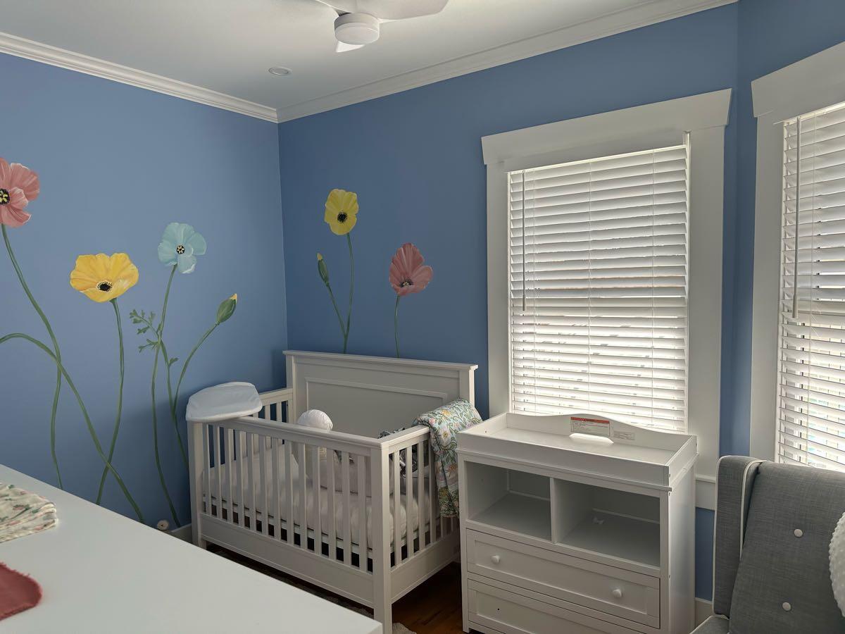Completed blue nursery with white trim, windows, ceiling fan, crib, and changing table