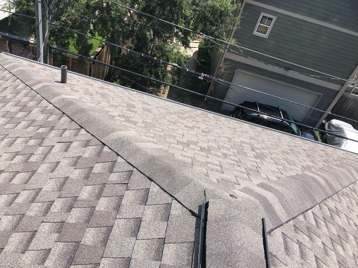 Wide view of the completed gray shingle roof and ridge cap